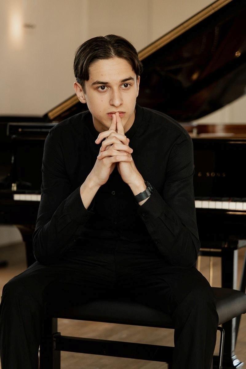 Ihor Panchenko mit dem Rücken zu einem Flügel sitzend